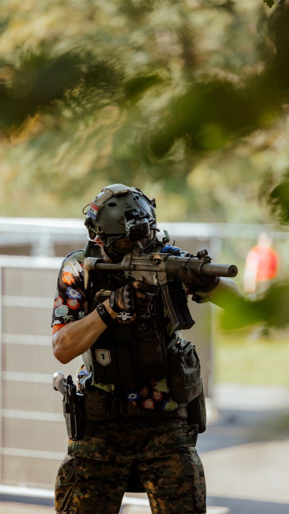 Airsofter met replica paraat tijdens een skirm op een outdoor locatie