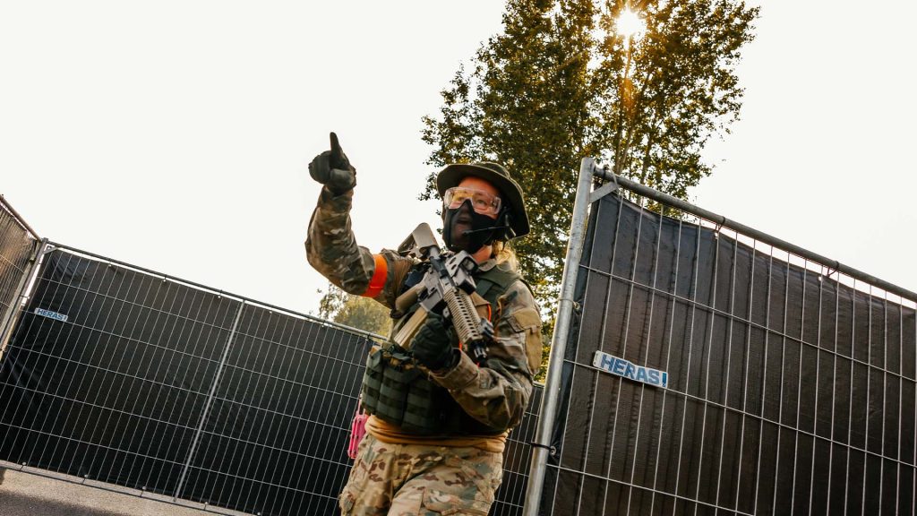 Vrouwelijke airsofter wijst tijdens de jubileumbeurs skirm in het veld